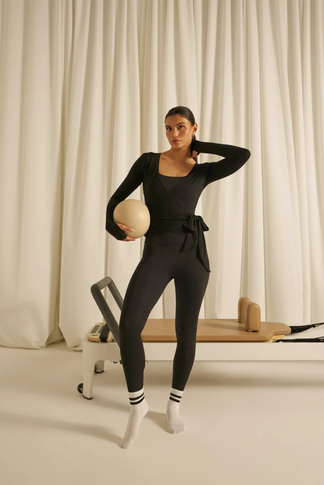 Model wearing an elegant black Pilates wrap top and leggings